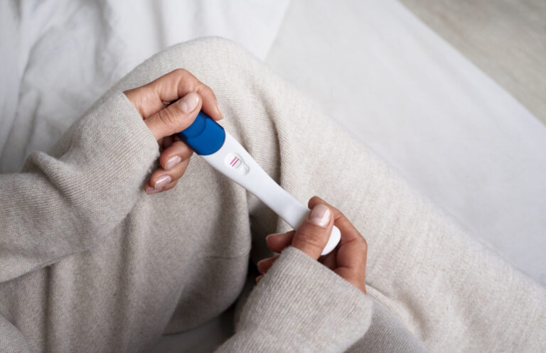 Woman holding a positive pregnancy test, highlighting the importance of birth control for women